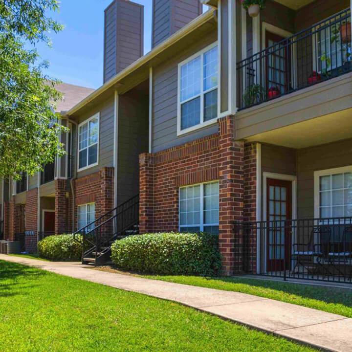 SBTX_exterior_gallery_jan23 outside of apartment building at summer brook with patio and balcony
